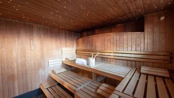 Una sauna con bancos de madera y techo inclinado con luces empotradas.