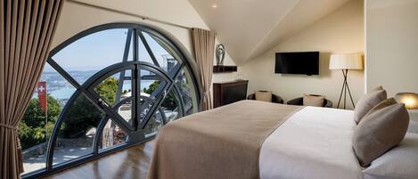 A hotel room with a large window, a bed, a TV, and a lamp.