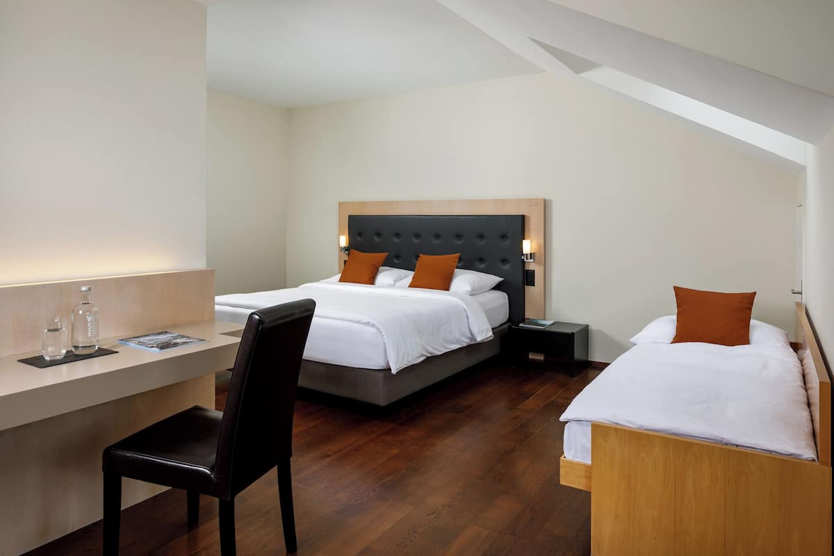 Une chambre d’hôtel avec un lit, un bureau, une chaise et une table de chevet.