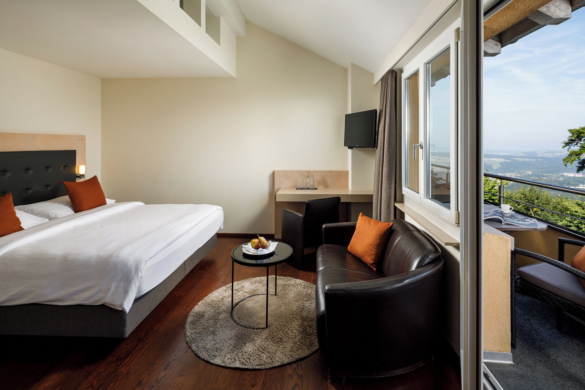 Een hotelkamer met een bed, een bureau, een stoel en uitzicht op het landschap.