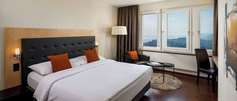 A hotel room with a large bed, a desk, and a chair.
