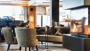 A modern living room with a fireplace, comfortable seating, and a large TV screen. - Wellness Hotel Alpenhof (Zermatt)