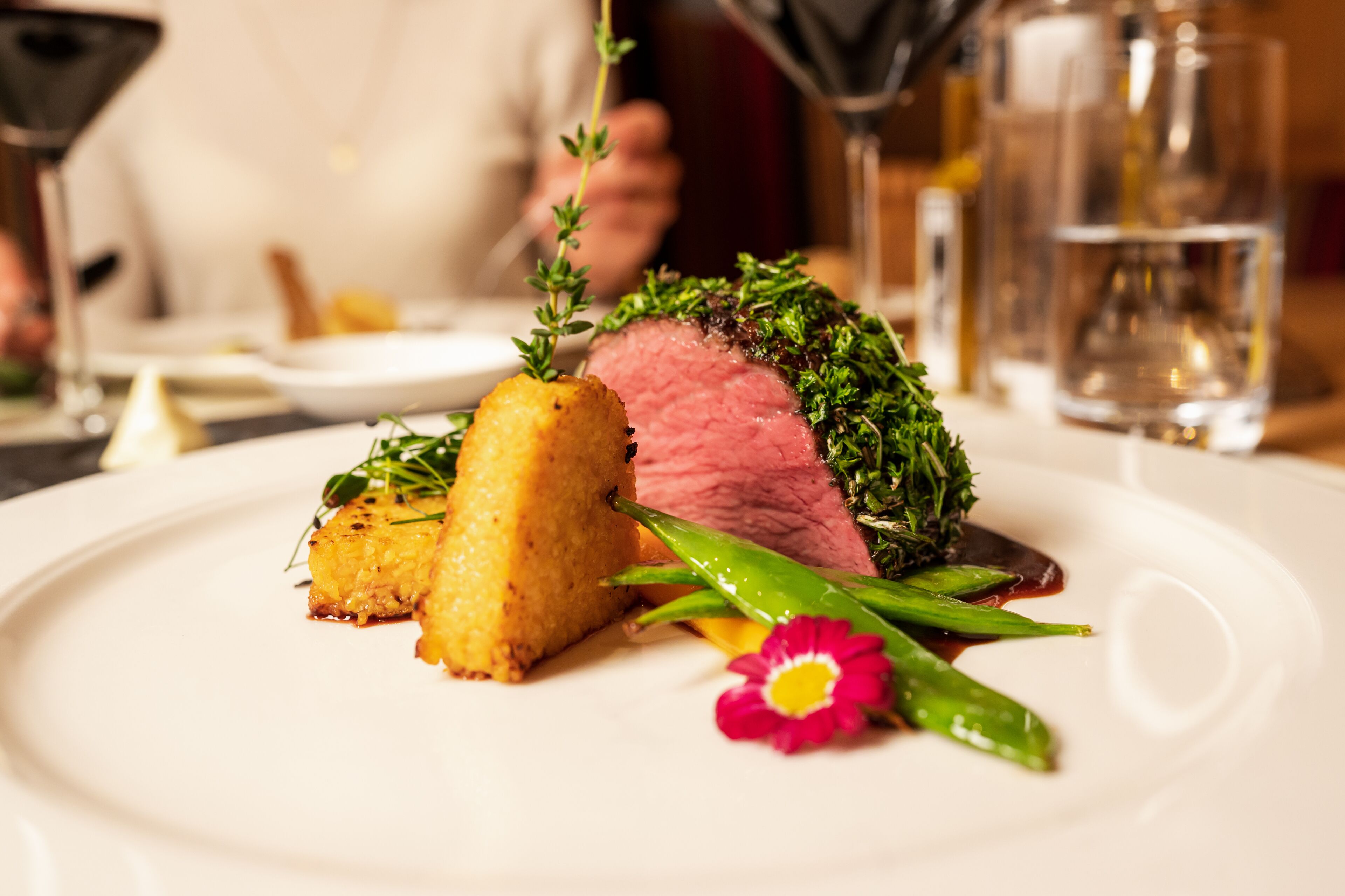 A plate with a slice of meat, a golden-brown item, and green garnish.