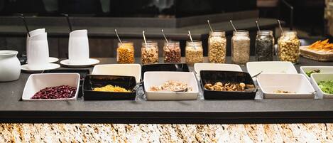 Mostrador de buffet con diversos alimentos y recipientes.