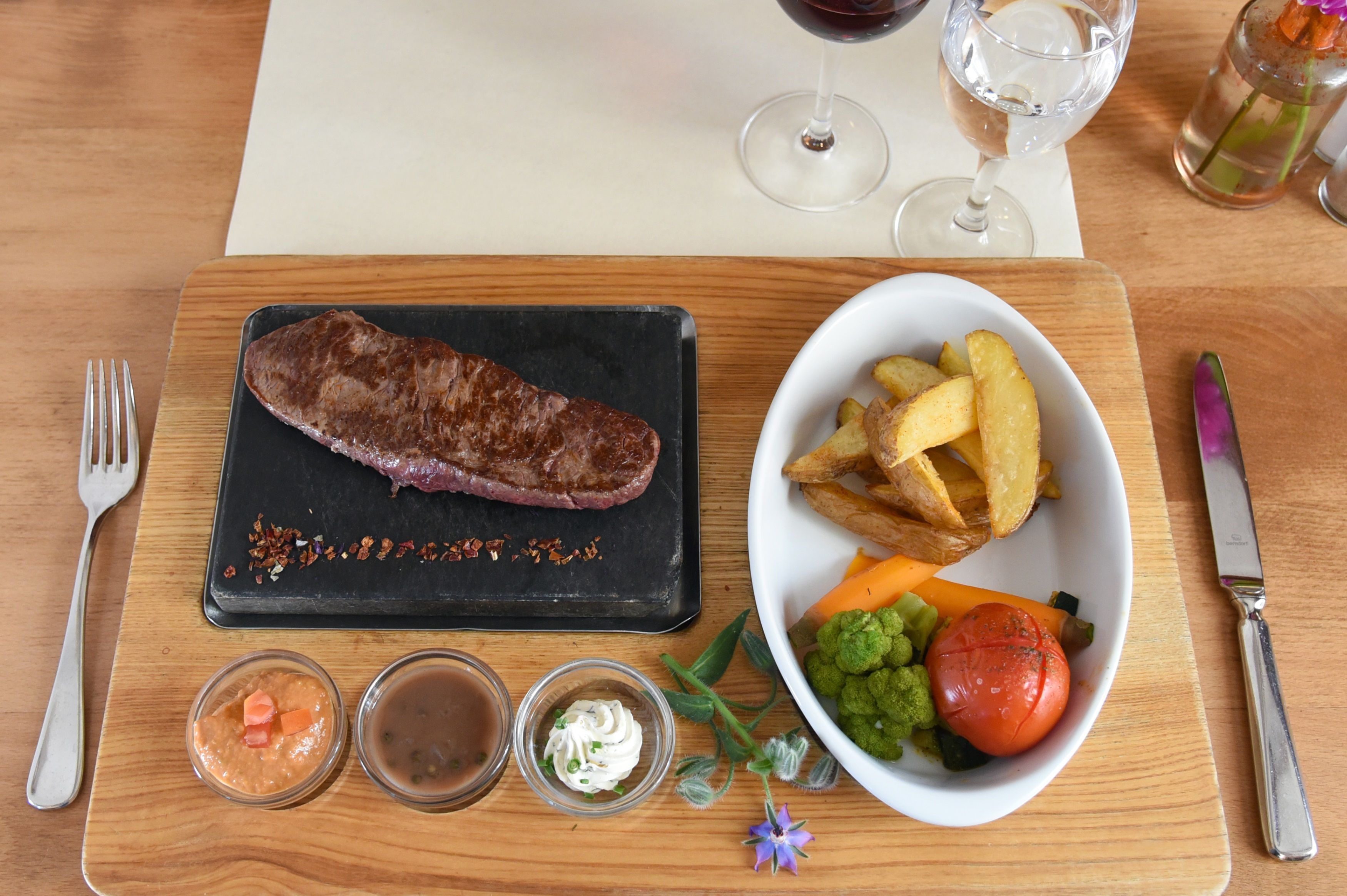 A meal with steak, potatoes, and vegetables on a wooden table.