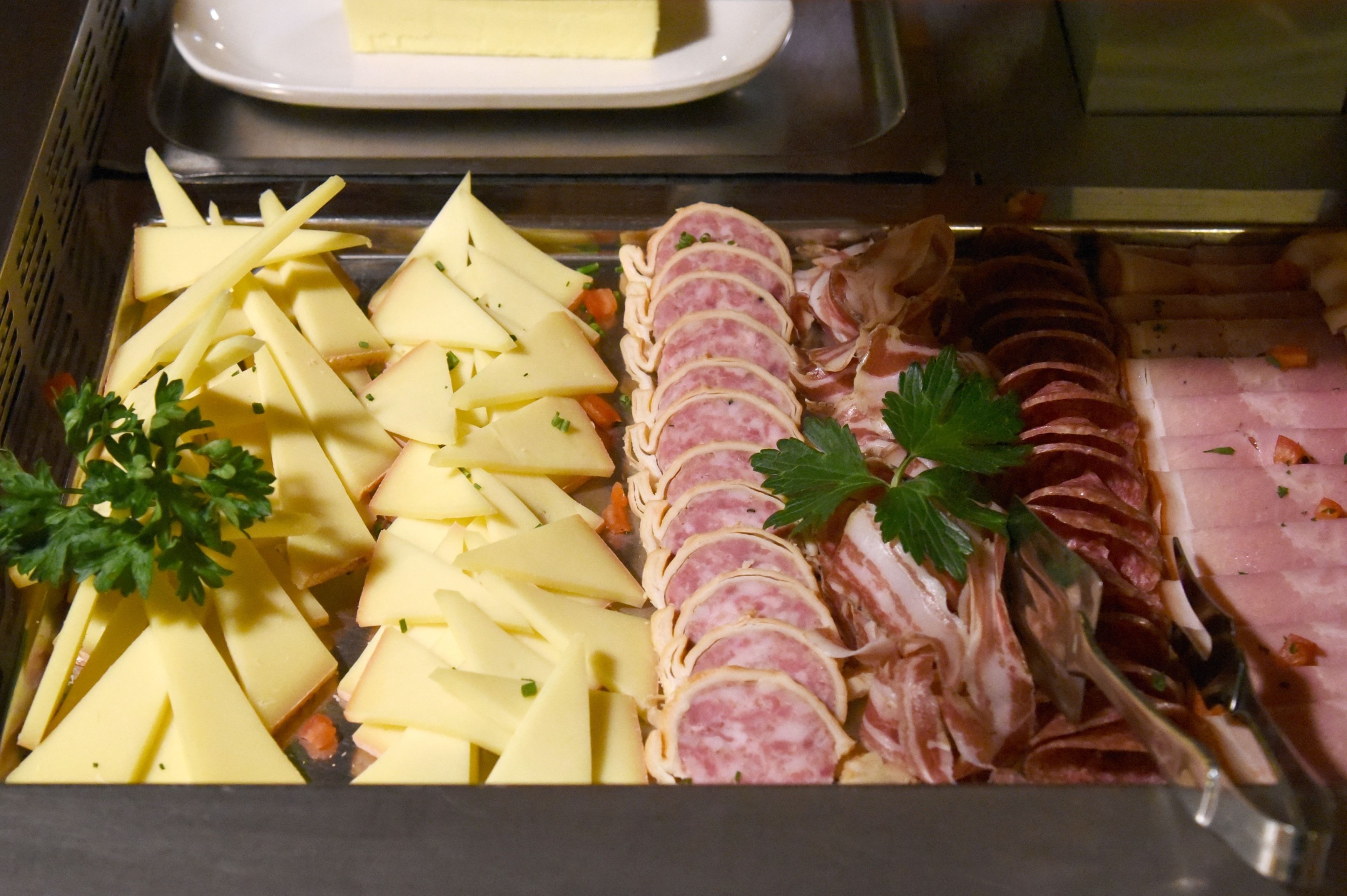 A buffet with sliced ham and cheese.