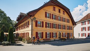 A two-story building with a yellow facade and red shutters, labeled "HOTEL DE LAIGLE." - Hôtel de l'Aigle (Val-de-Travers)