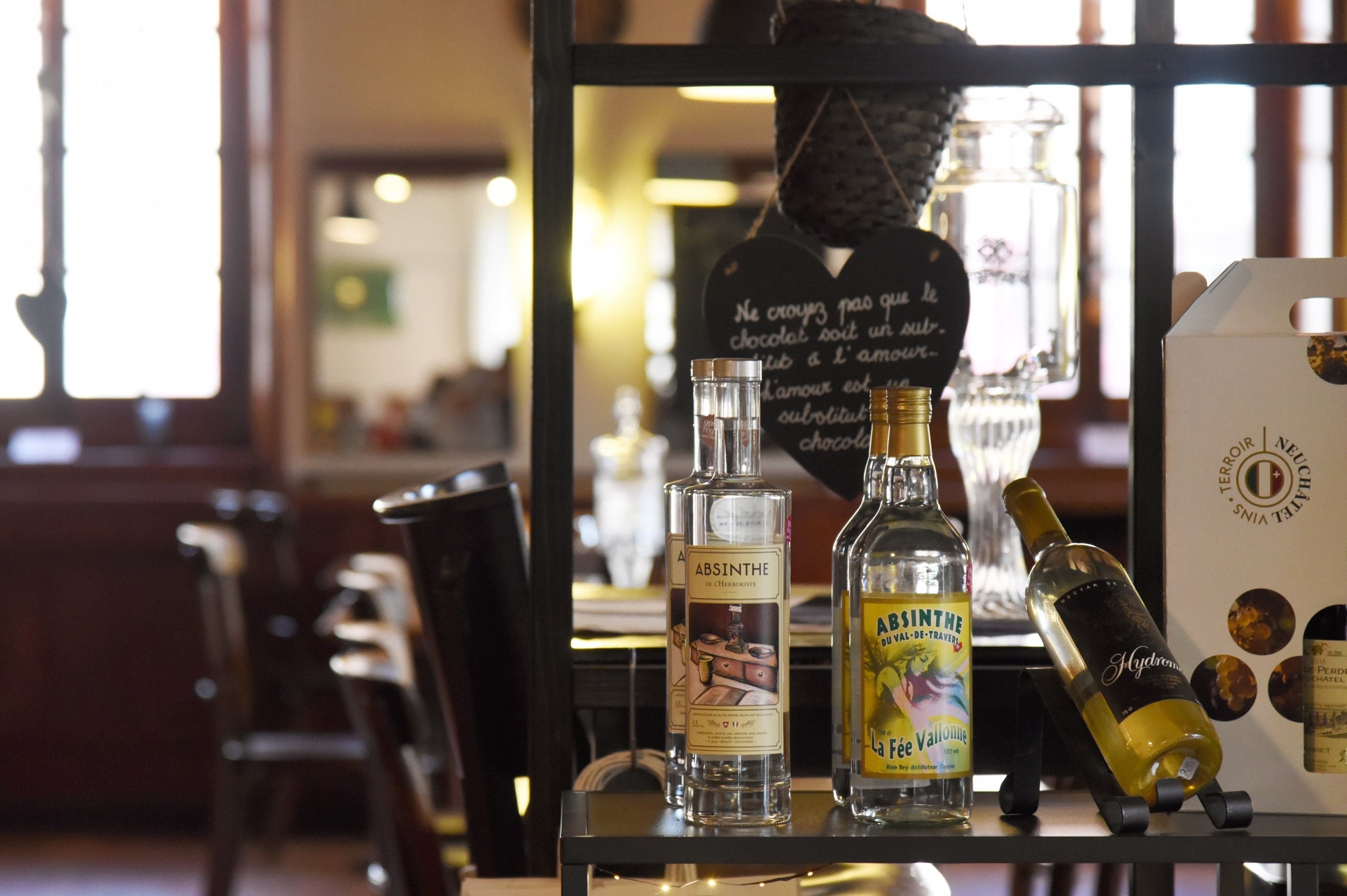 A bar area with bottles of liquor, a mirror reflecting the interior, and a chalkboard with writing.