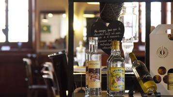 A bar area with bottles of liquor, a mirror reflecting the interior, and a chalkboard with writing.