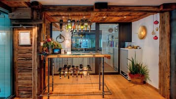 Un intérieur rustique avec un plafond en bois, un coin bar avec des bouteilles et une plante en pot.