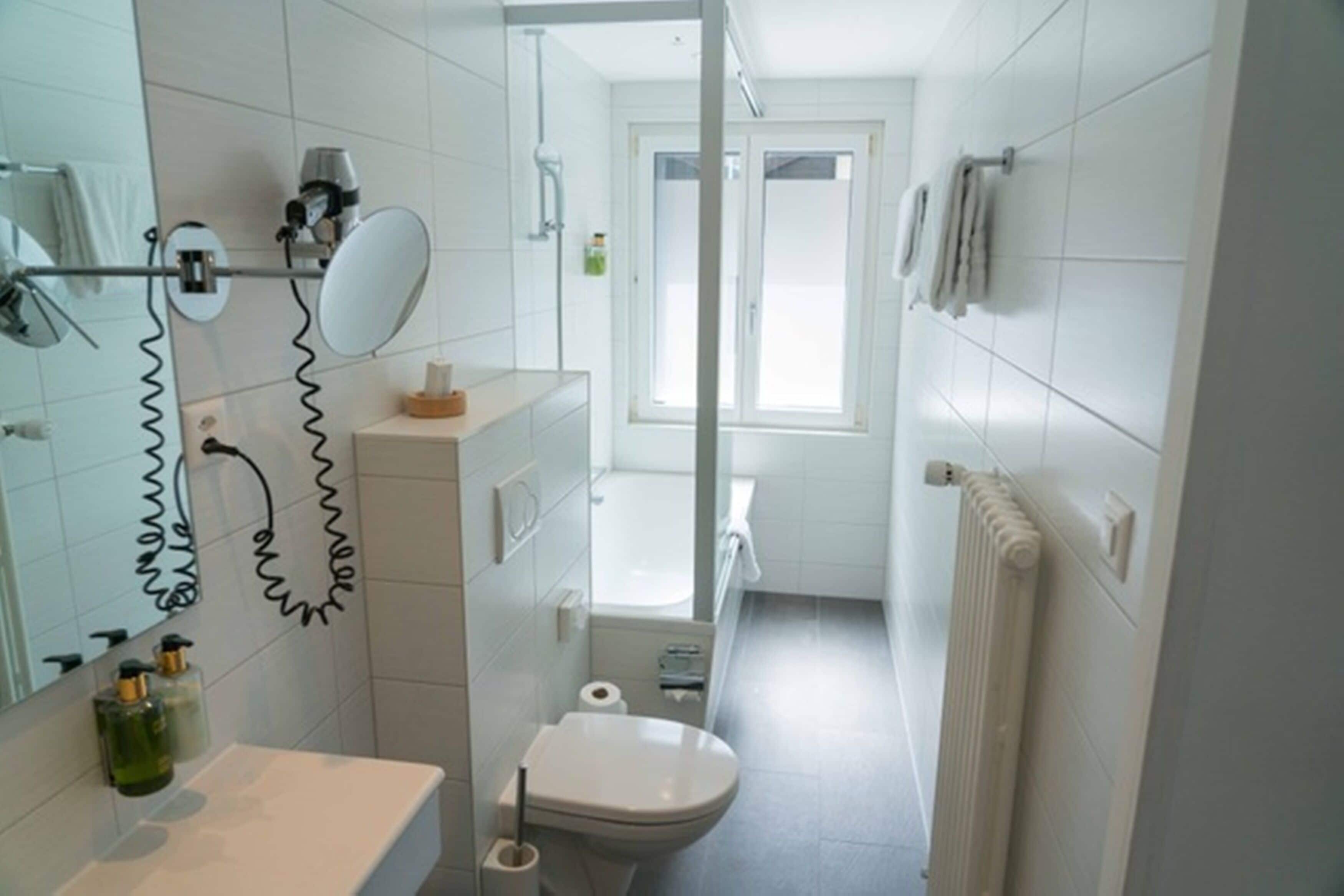 Un baño con inodoro, lavabo, espejo y toallero.