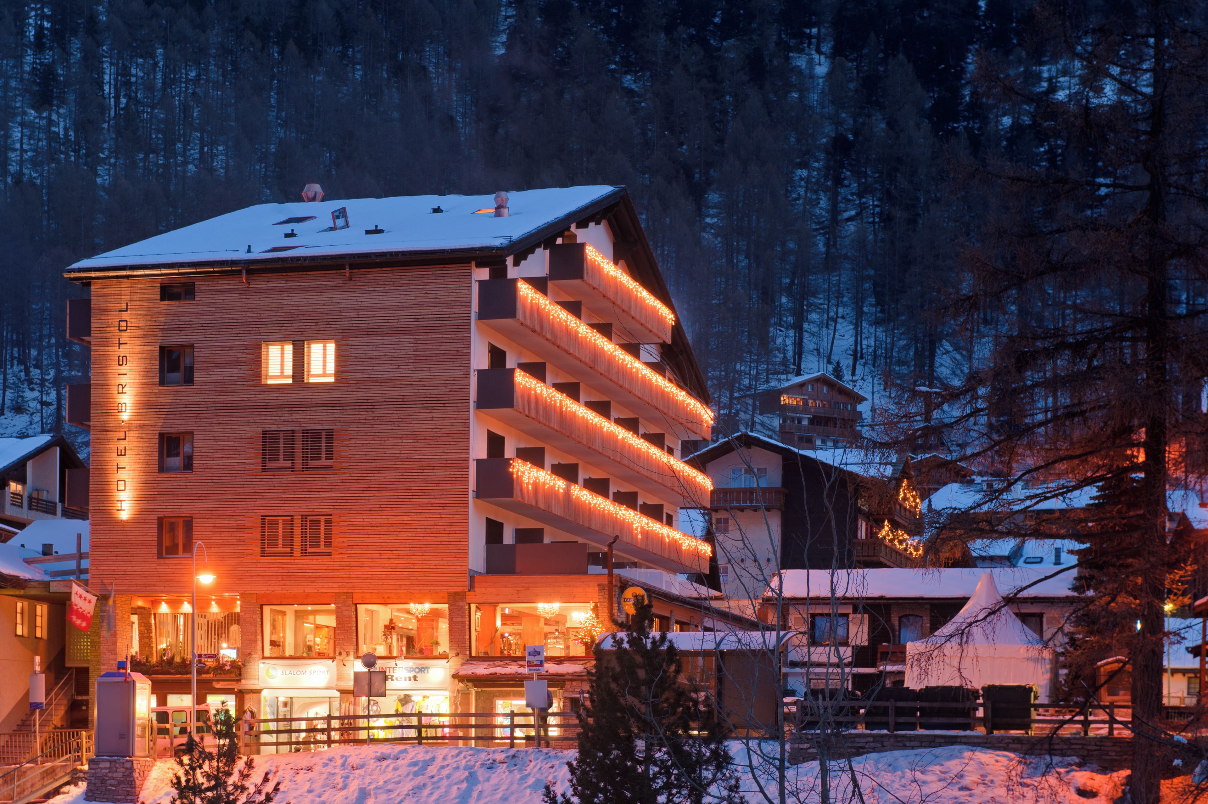 A multi-story hotel with a wooden facade and balconies adorned with string lights.