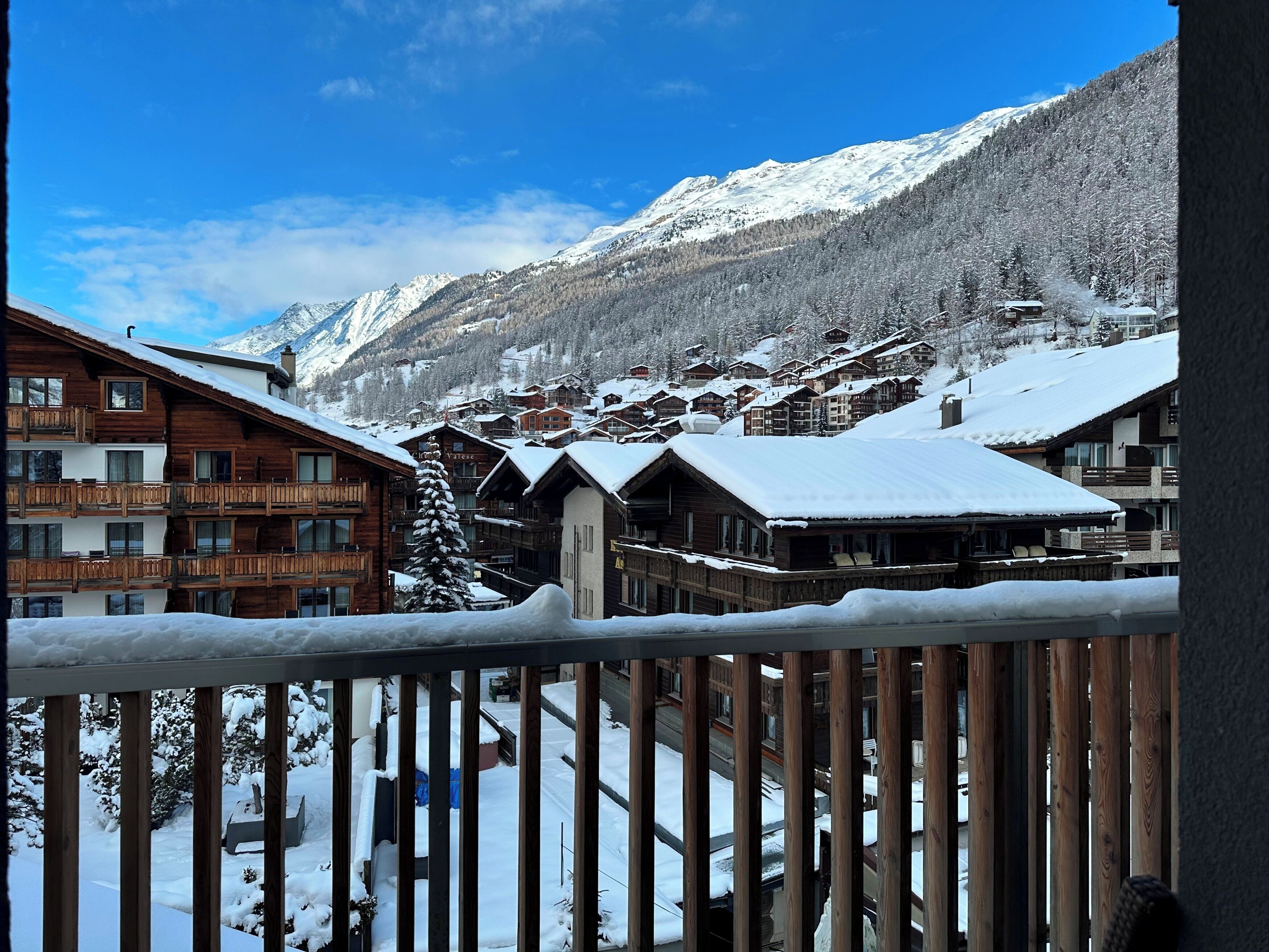 Un villaggio montano innevato con case di legno e un cielo azzurro limpido.