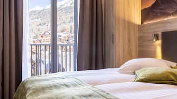 Habitación de hotel con cama, cortinas, vistas a la montaña y una pared de madera.