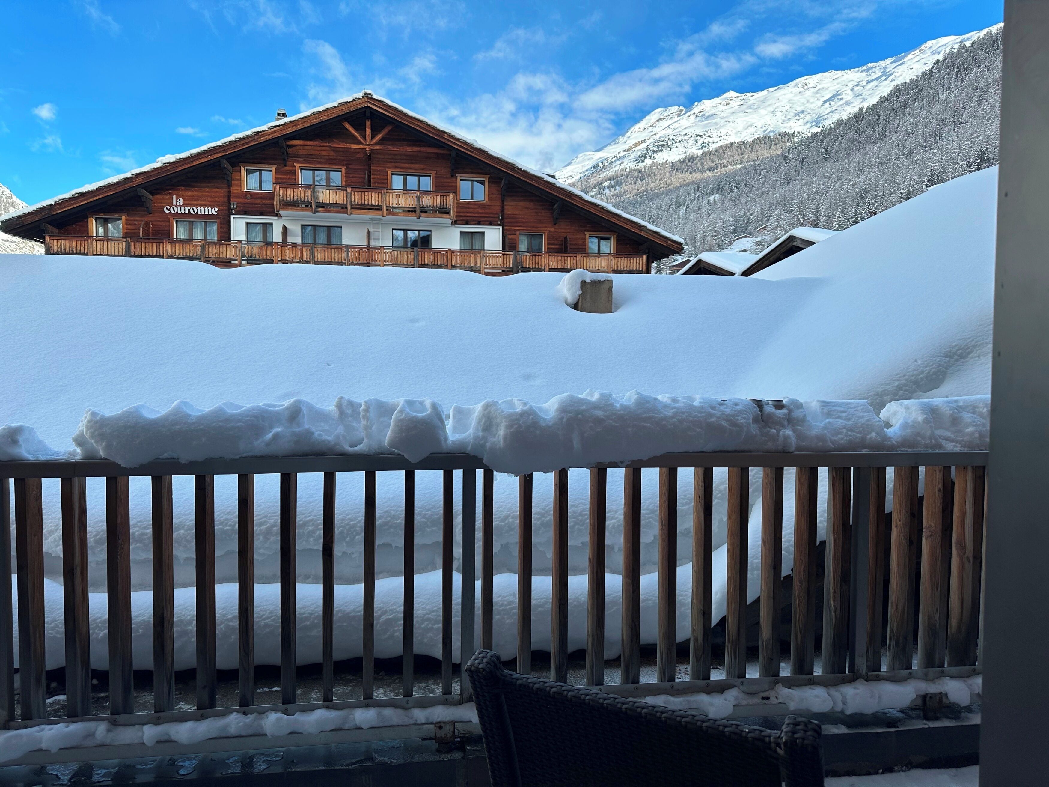 Una cabaña de madera con balcón, rodeada de montañas nevadas.