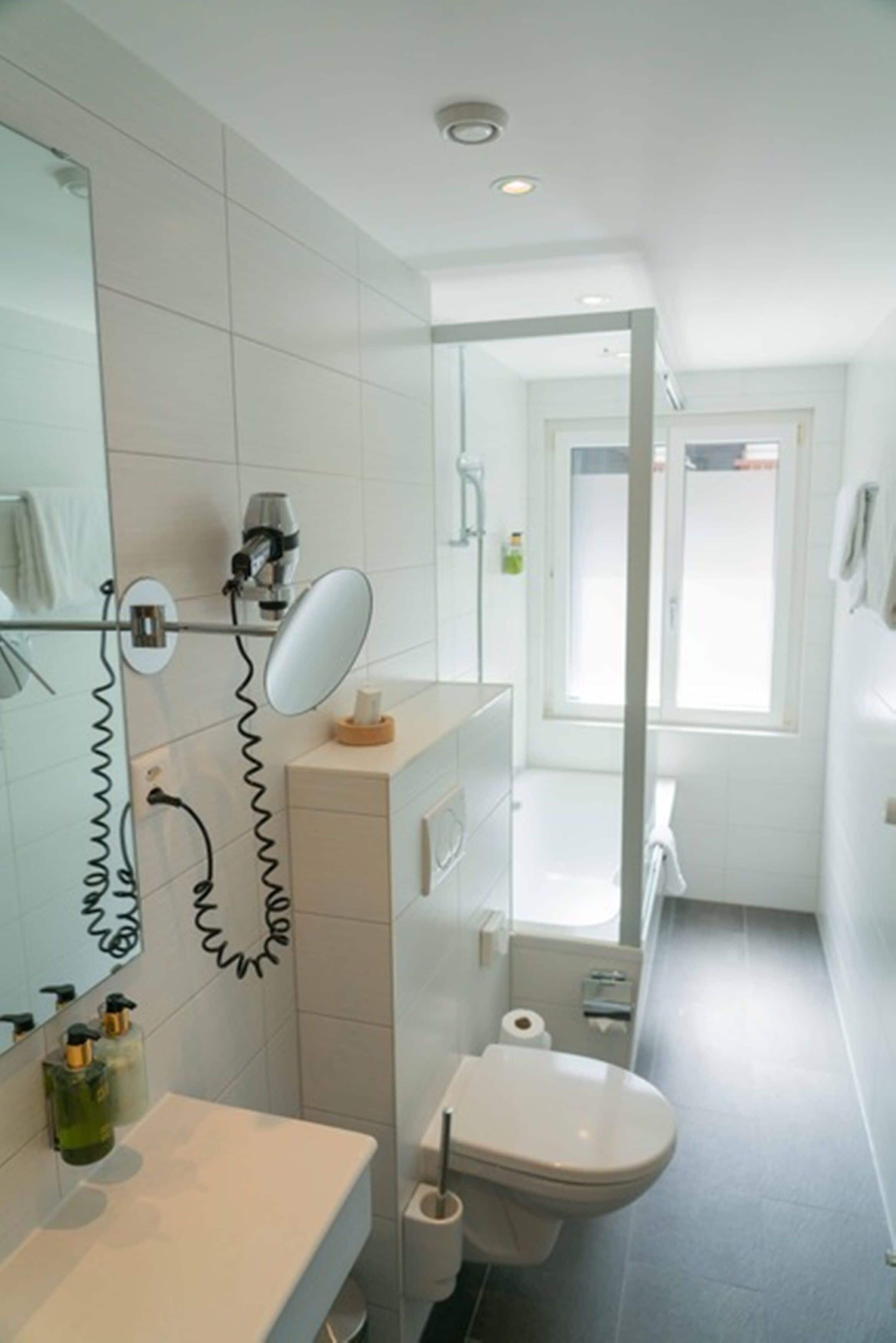 A bathroom with a toilet, sink, mirror, and shower area.