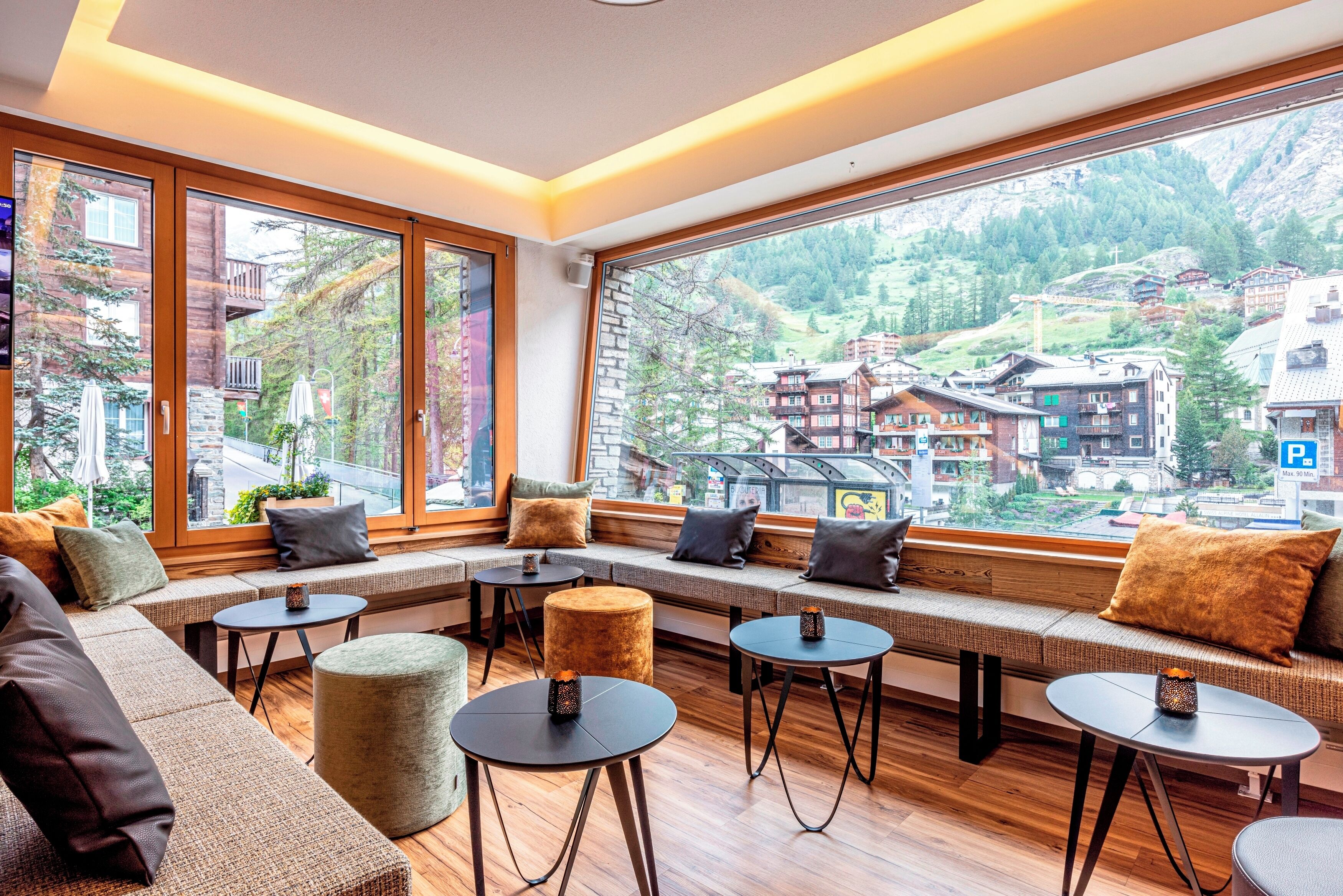 A modern interior with large windows offering a view of a mountainous village.