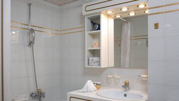 A bathroom with a shower, a sink, and a mirror with lights.