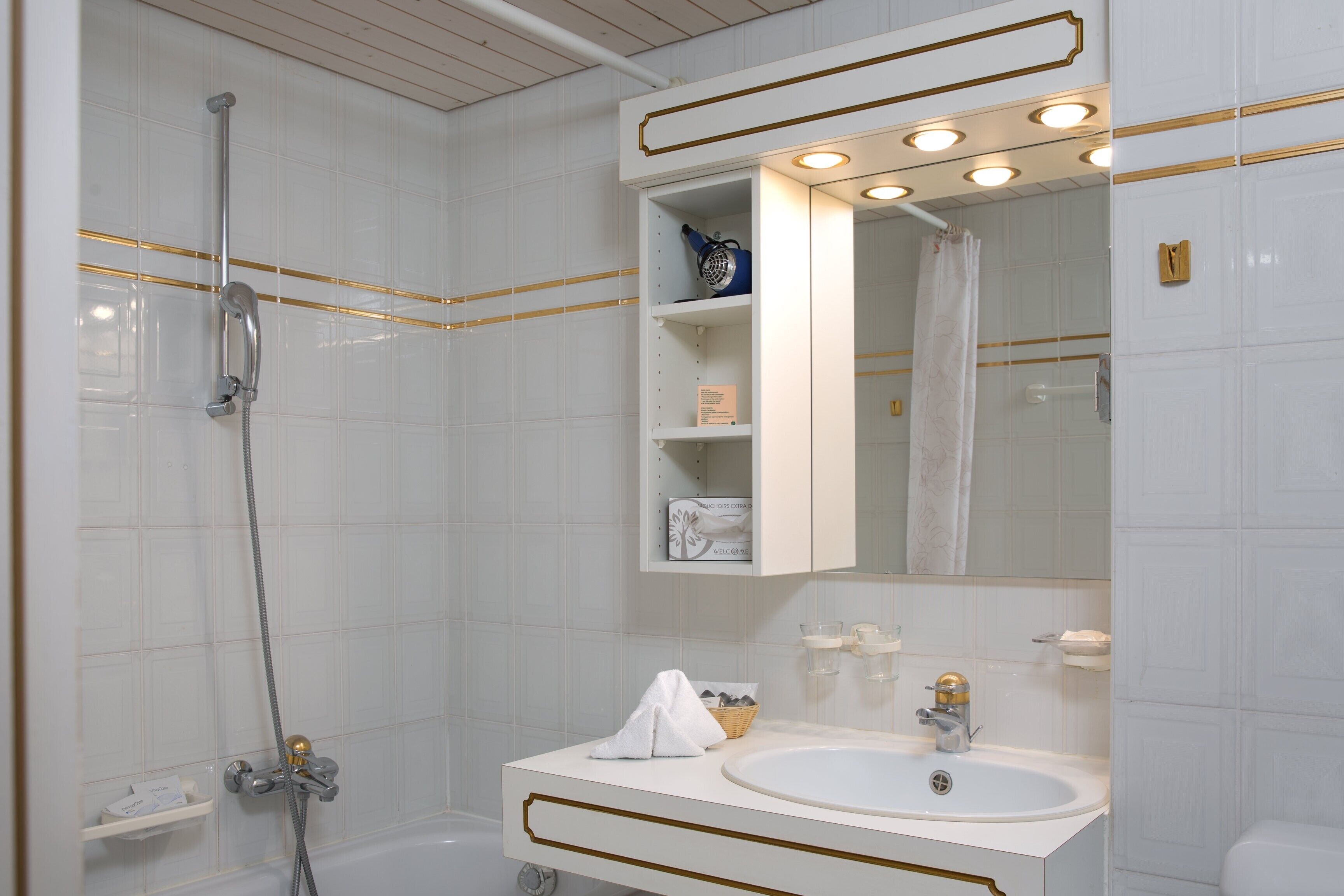 Un baño moderno con bañera, lavamanos y espejo con iluminación.
