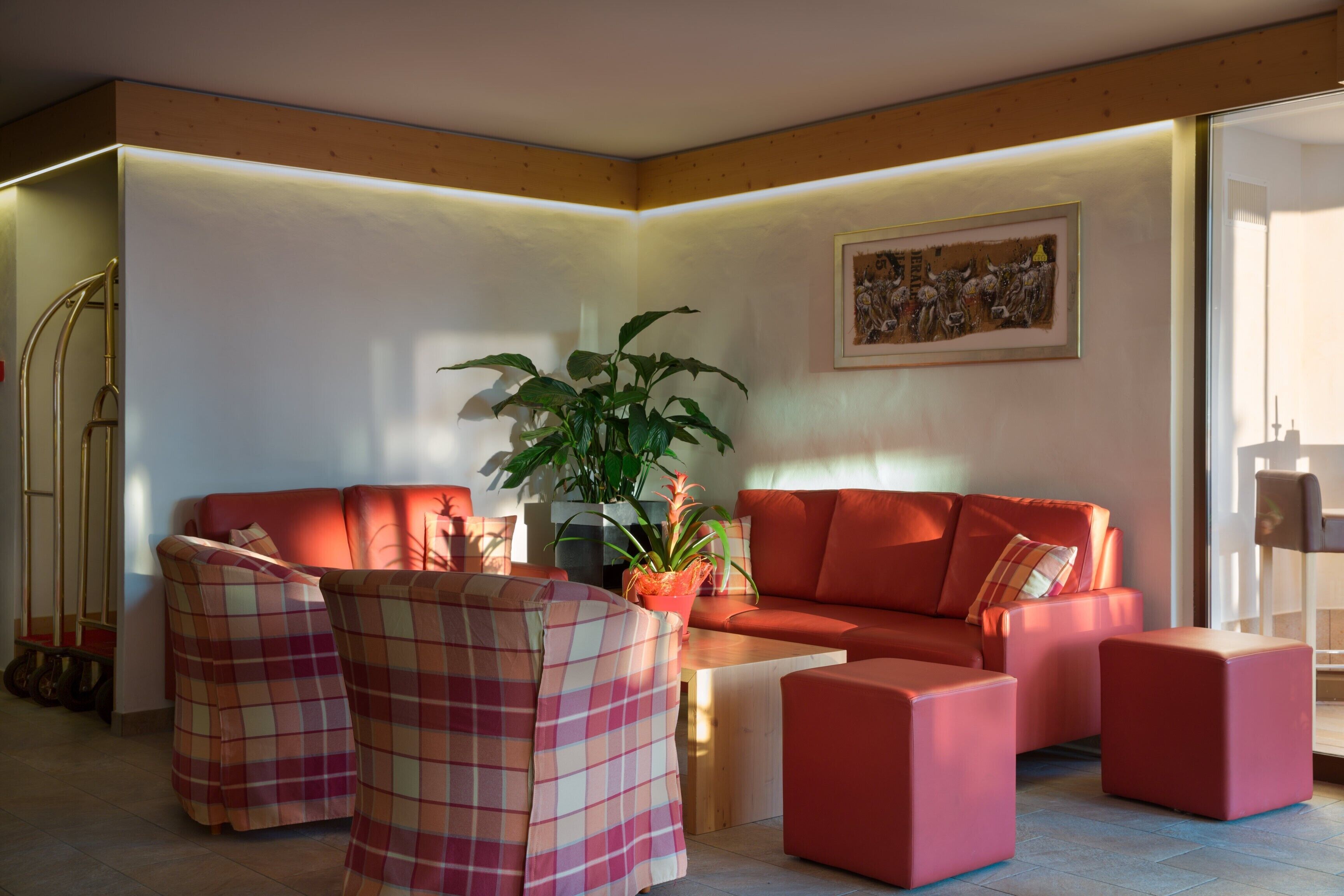 Een moderne woonkamer met een rode bank, geruite fauteuils en een salontafel.