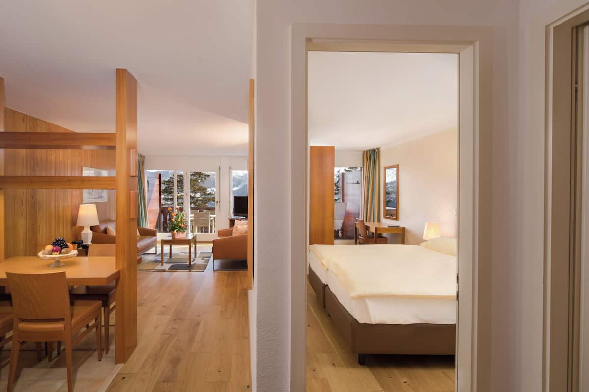 A hotel room with a wooden dining area, a bed, and a view of the outdoors.