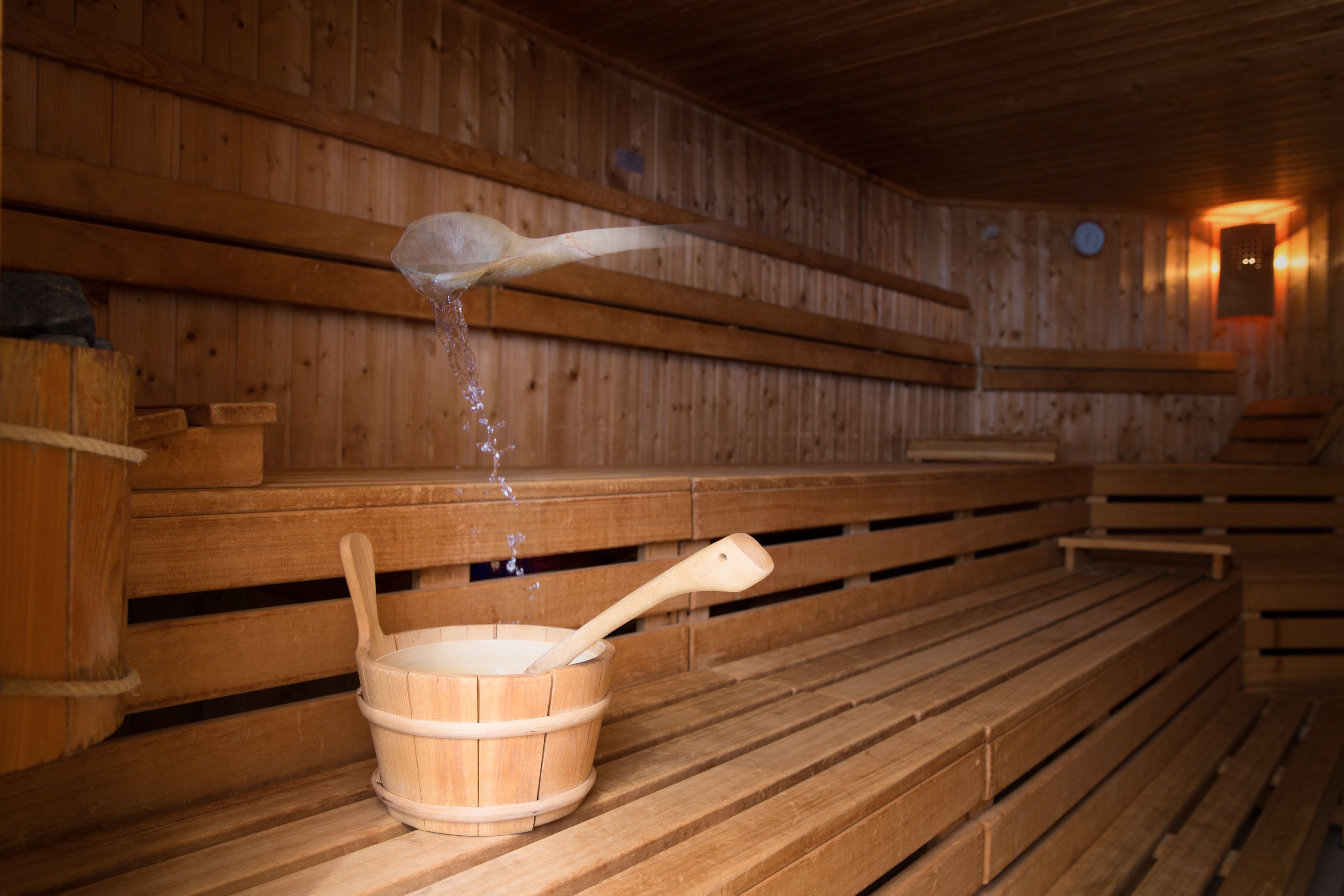 A wooden sauna with benches and a wooden bucket with a ladle.