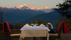 A table set for two with a mountain view in the background. - Hotel Helvetia Intergolf (Crans-Montana)