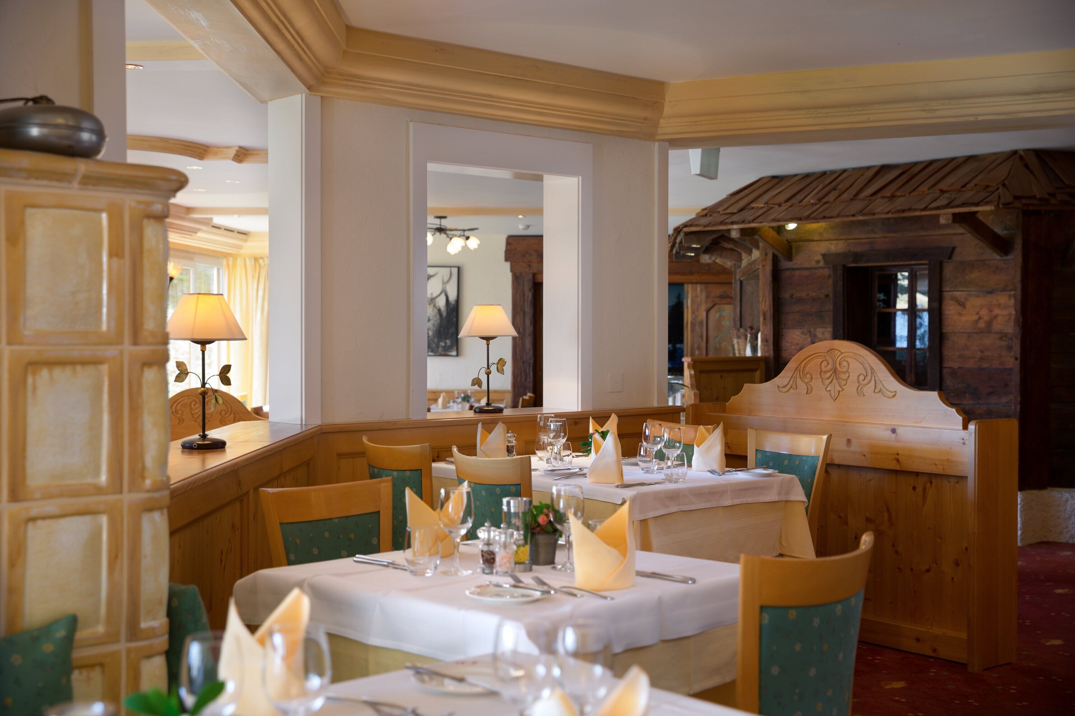 Un espace repas avec des tables et des chaises en bois, des nappes blanches et des couverts disposés avec soin.