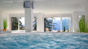 A spa area with a hot tub, large windows, and indoor plants. - Hotel Helvetia Intergolf (Crans-Montana)