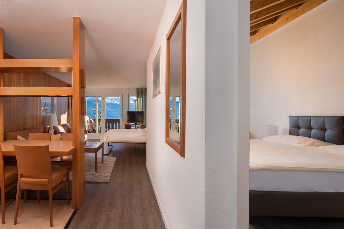A hotel room with a wooden desk, a bed, and a view of mountains.