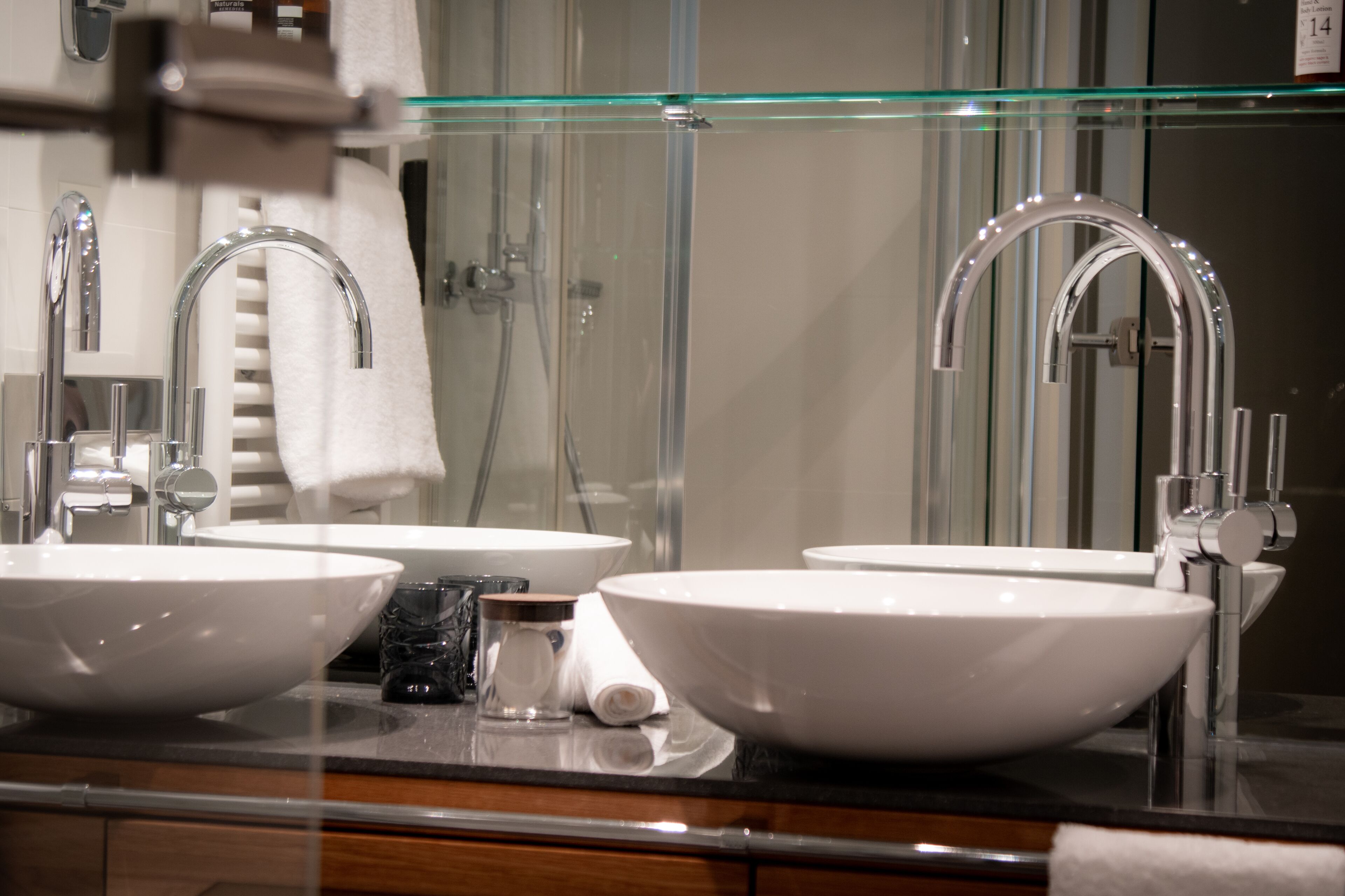 Ein Badezimmer mit zwei Waschbecken, einer Glasablage darüber und einem Handtuchhalter.