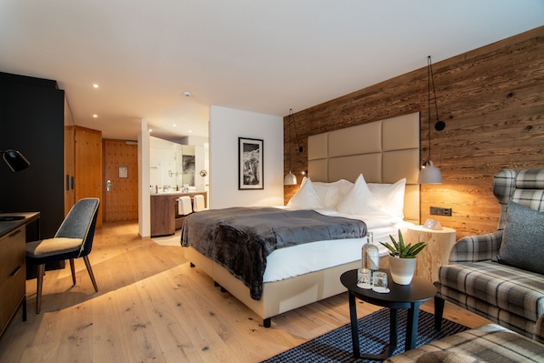 A modern bedroom with a large bed, a bedside table, a chair, and a wooden accent wall.
