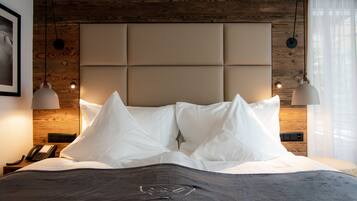 A neatly made bed with a padded headboard, a bedside telephone, and pendant lights.