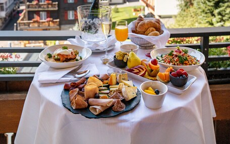 A table set with breakfast items and a glass of orange juice, overlooking a mountainous landscape.