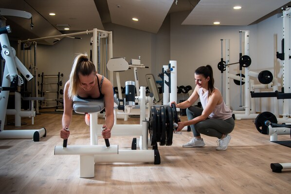 Un gimnasio con varios equipos de ejercicio, incluyendo una prensa de banca y estantes para pesas.