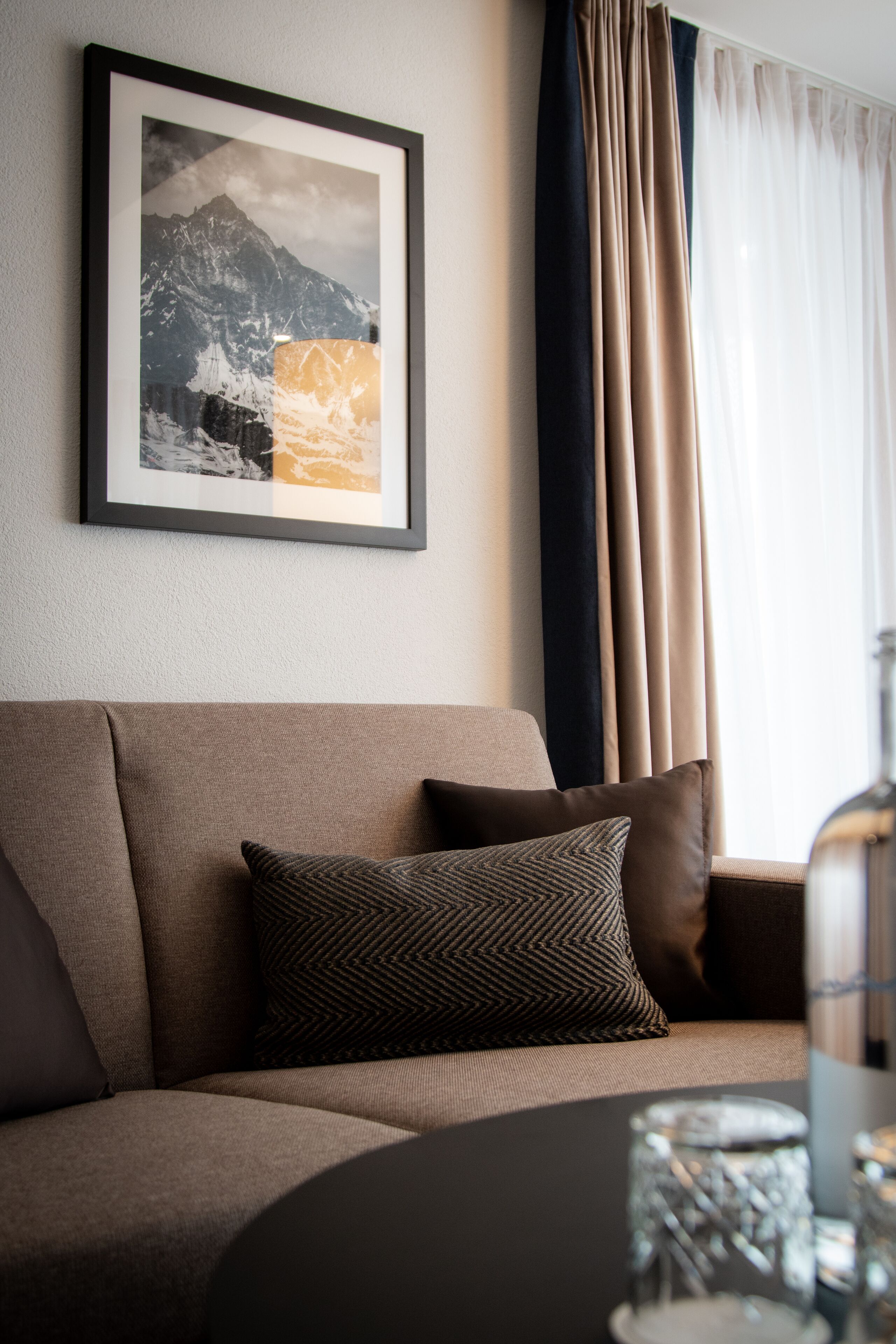 En moderne stue med sofa, et indrammet billede på væggen og et sofabord med et lys.