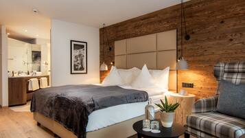 Ein modernes Schlafzimmer mit einem großen Bett, einer Wand mit Holzverkleidung, einem Nachttisch mit Pflanze und einem karierten Sessel.