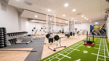 Une salle de sport équipée de divers appareils d’entraînement, notamment des machines de musculation, des tapis de course et une barre de traction.