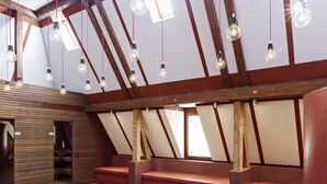 Un interno moderno con soffitti spioventi, travi in legno e diverse zone relax con panche imbottite.
