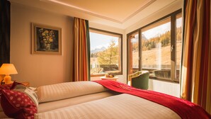 Habitación de hotel con dos camas, una ventana con vista a la montaña, un cuadro en la pared y una lámpara en la mesita de noche.