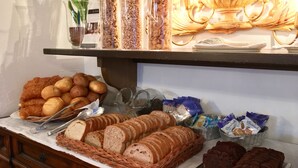 Un bufé con panes, pasteles y salsas variadas.