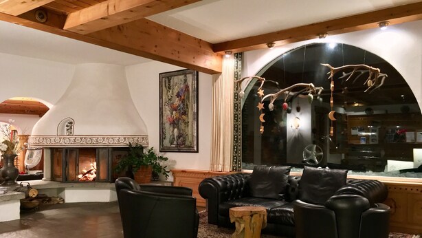 Una sala de estar acogedora con chimenea, sofás de cuero y techo de madera rústica.