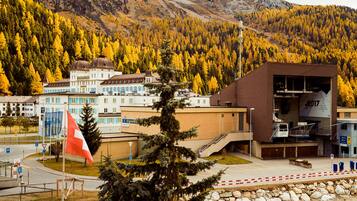 Un edificio de diseño moderno, una bandera y montañas al fondo.