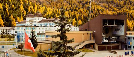 A building with a modern design, a flag, and a mountainous backdrop.