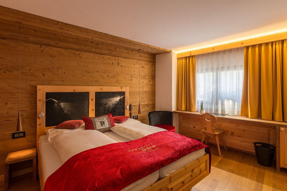 A wooden-paneled room with a bed, a desk, and a chair.