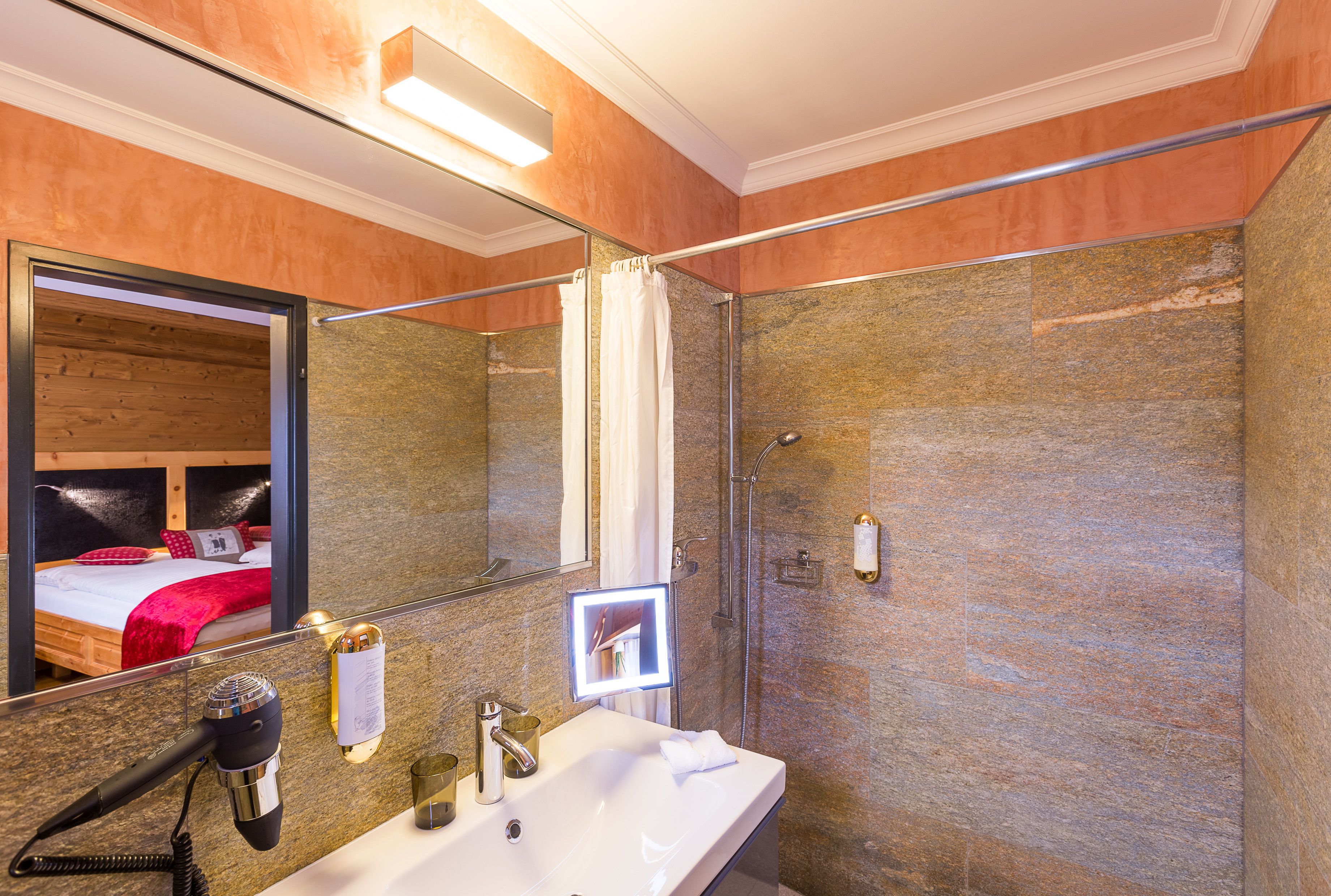A bathroom with a shower, a sink, and a hairdryer.