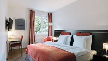 A hotel room with a bed, a desk, a chair, a TV, and a window with curtains.