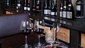 A wine cellar with shelves stocked with wine bottles and glasses on a table.