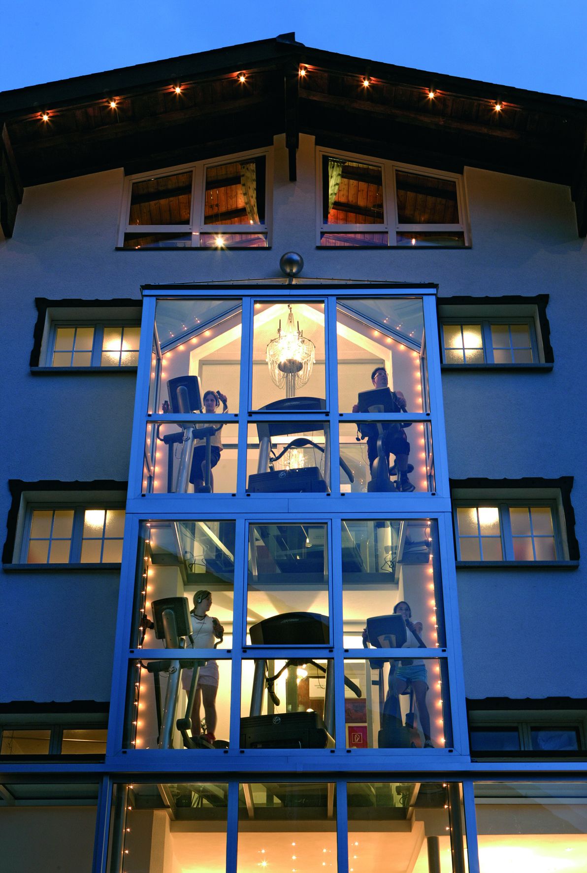 A multi-story building with a central atrium featuring a chandelier and multiple windows.