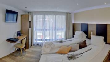 Ein Hotelzimmer mit zwei Betten, einem Schreibtisch und einem Fernseher.